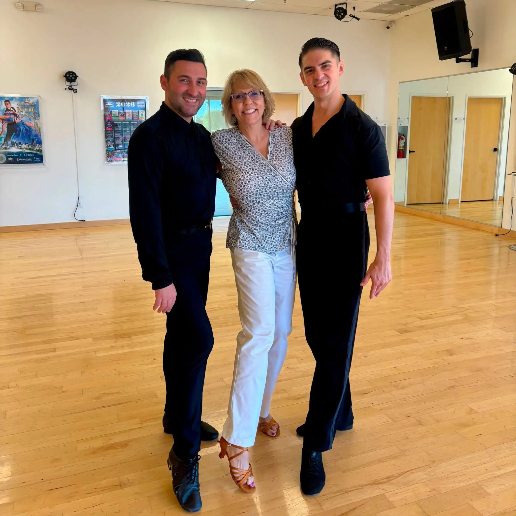Three people pose together in a dance studio, highlighting a Beginner's Guide to Swing Dancing with instructors dressed in black and a participant in white pants and a patterned top.