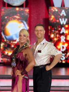 Celebrating Five Medals for Fred Astaire Dance Studios – Apex: A smiling ballroom dance couple proudly displays their competition medals, celebrating their achievements with Fred Astaire Dance Studios – Apex.