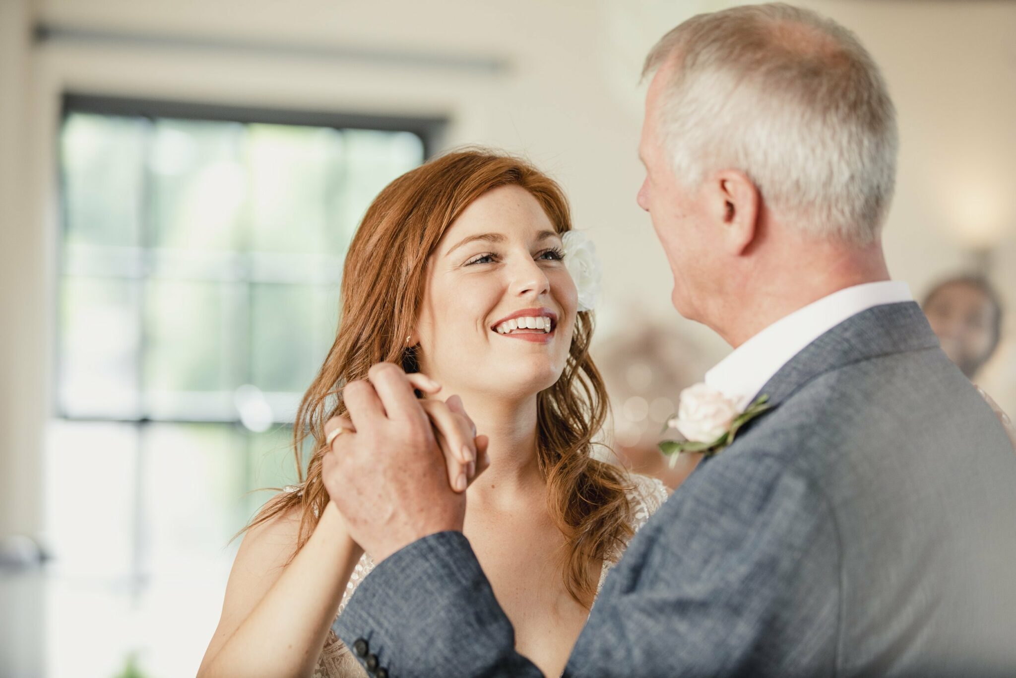 A bride smiles at her father as they enjoy a father and daughter dance at her wedding.