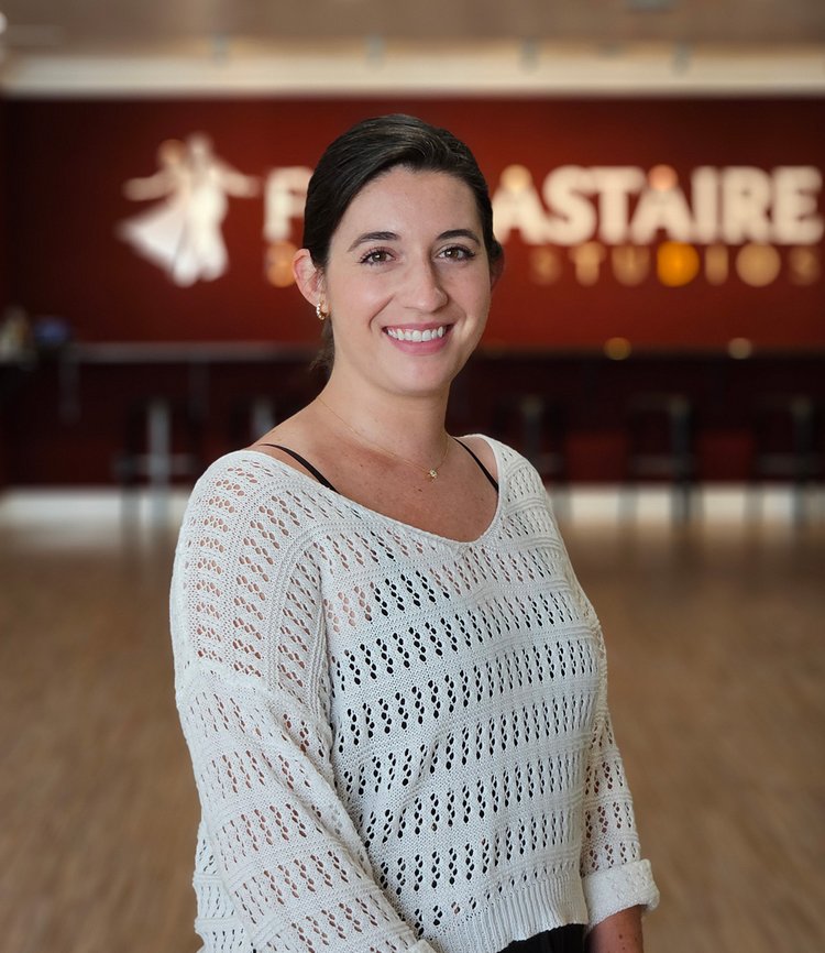 Certified instructor Sydney Radcliffe smiles in front of the Fred Astaire dance studio logo at in downtown Boise.