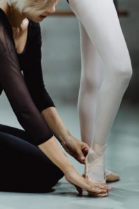 Dance instructor teaching ballerina proper form and foot placement.