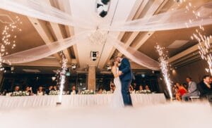 Young couple dancing at their wedding; sparklers and elegant decor surrounding the dance floor.