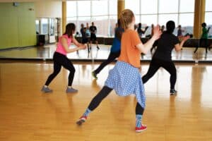 People participating in a dance class in a mirrored room.