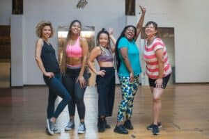 Group of women wearing athletic attire and posing in a dance studio.
