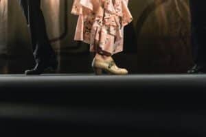 Close view of a couple's shoes as they stand on a dance floor.
