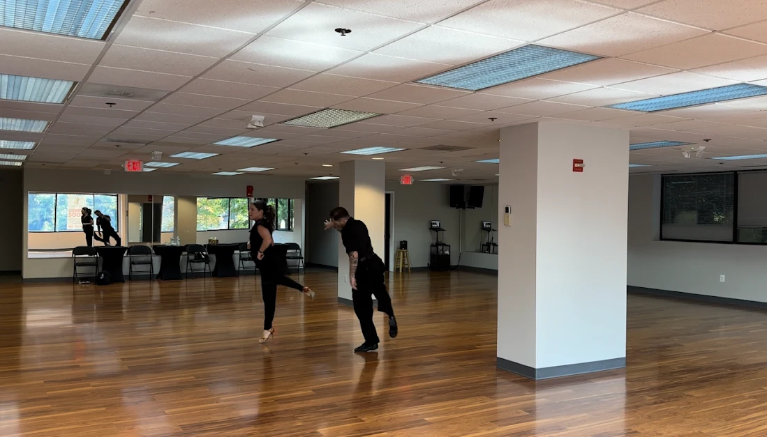 Spacious dance studio with wooden floors and mirrored walls used for ballroom dance lessons and practice sessions.