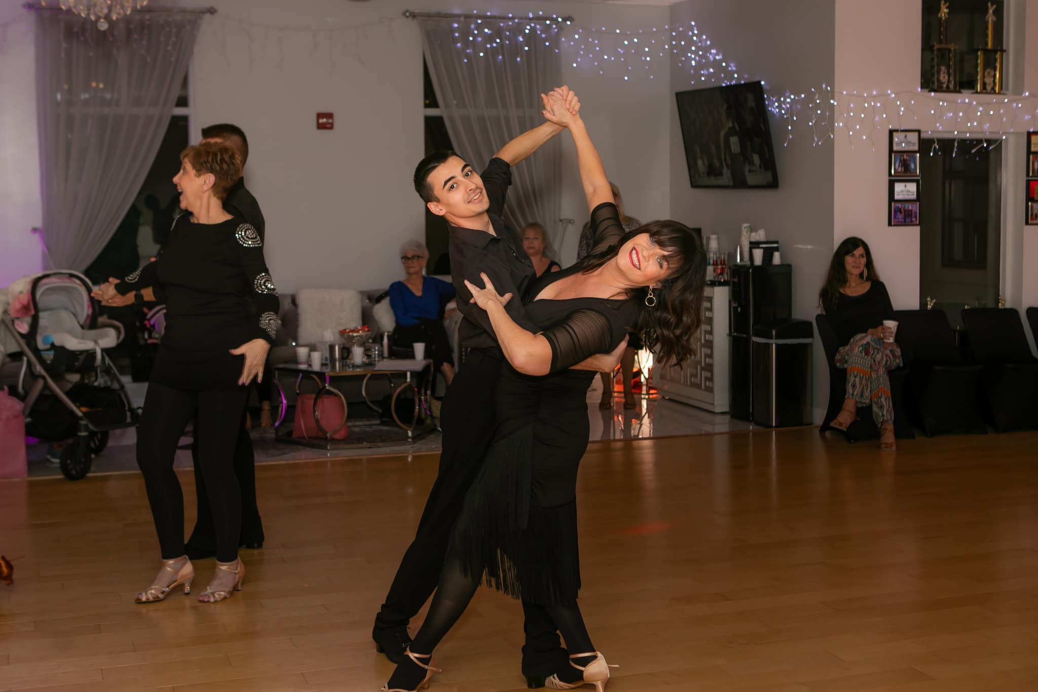Couple demonstrating proper dance frame during a ballroom dance in a studio.