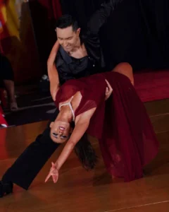 Learn Argentine Tango: A couple performs a dramatic Argentine tango dip, with the woman in an elegant burgundy dress and the man in black, demonstrating the passion and technique of tango dancing.