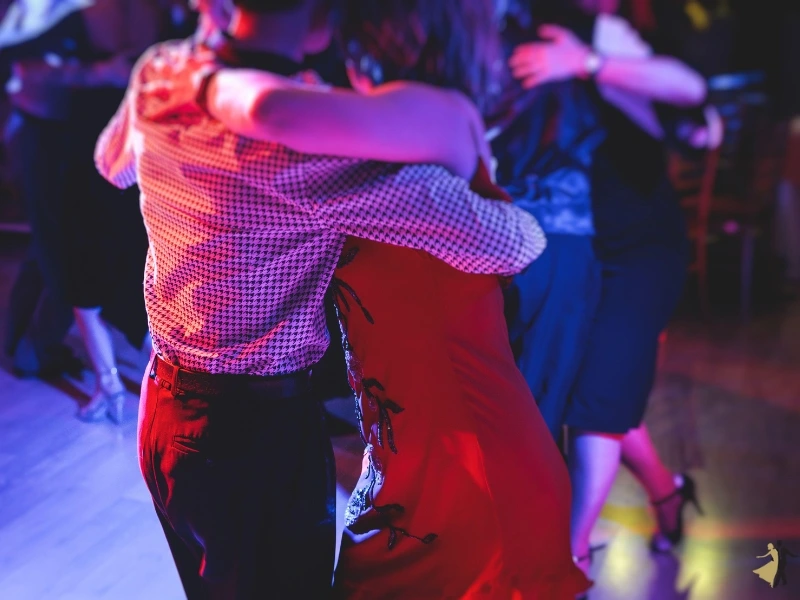 Couples dancing Latin dance in red and purple lighting. Salsa is a favorite dance style in Durham.