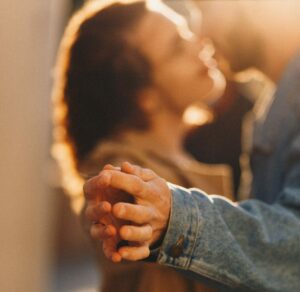 Woman and man dancing together, touching their hands together and smiling.