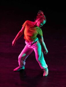 Woman dancing in dark studio alone.