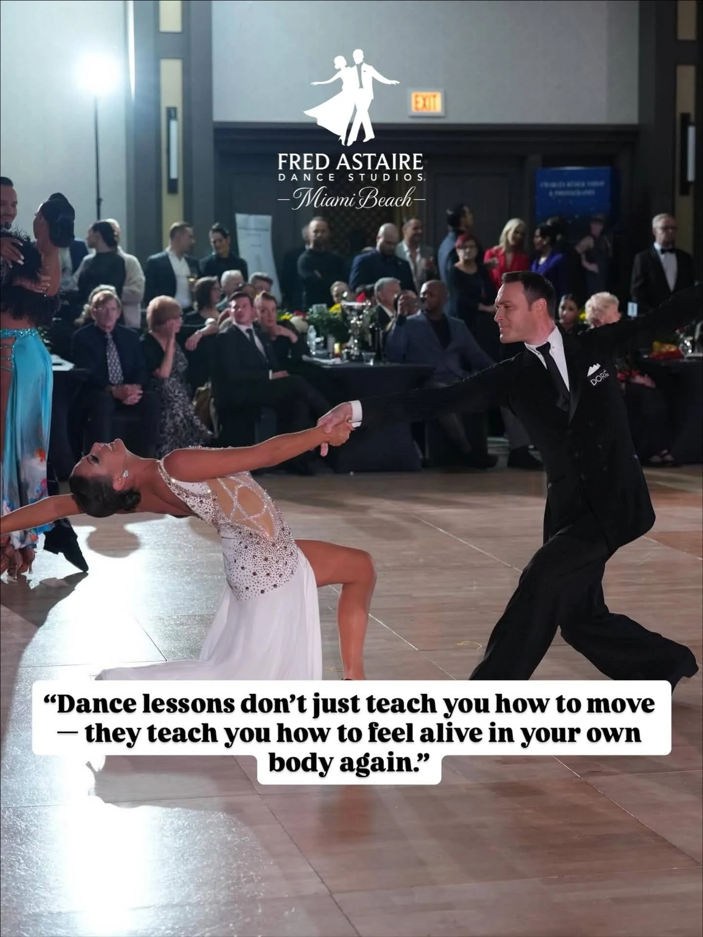 A ballroom dance couple performs a dramatic dip during a competition, with the female dancer in a sparkling white dress and the male dancer in a classic black suit extending her gracefully across the dance floor. Spectators watch from the background as the performance showcases the elegance and confidence that come from dance lessons in North Miami FL. A motivational quote about dance is displayed across the bottom of the image.