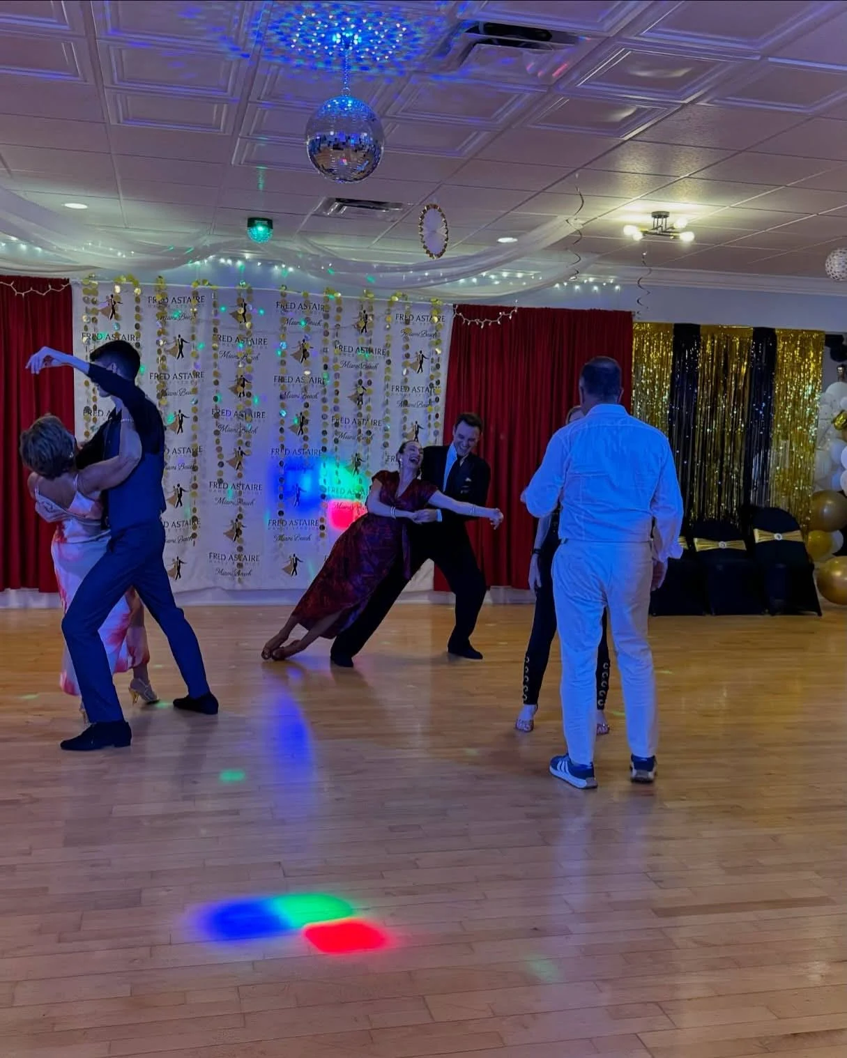 Well-dressed people in stylish suits and dresses attending Ballroom Dance Lessons in Miami.