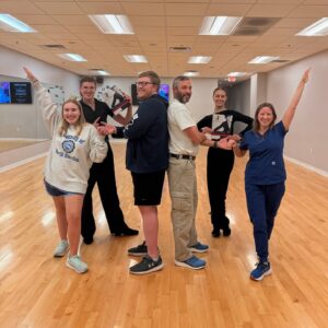 Students and instructors posing together during ballroom dance classes in Morrisville at a Fred Astaire Dance Studios location, highlighting a fun and welcoming community for beginner and social dancers.