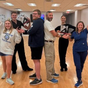 Adult students holding a beginner program guide during ballroom dance classes in Morrisville, NC.