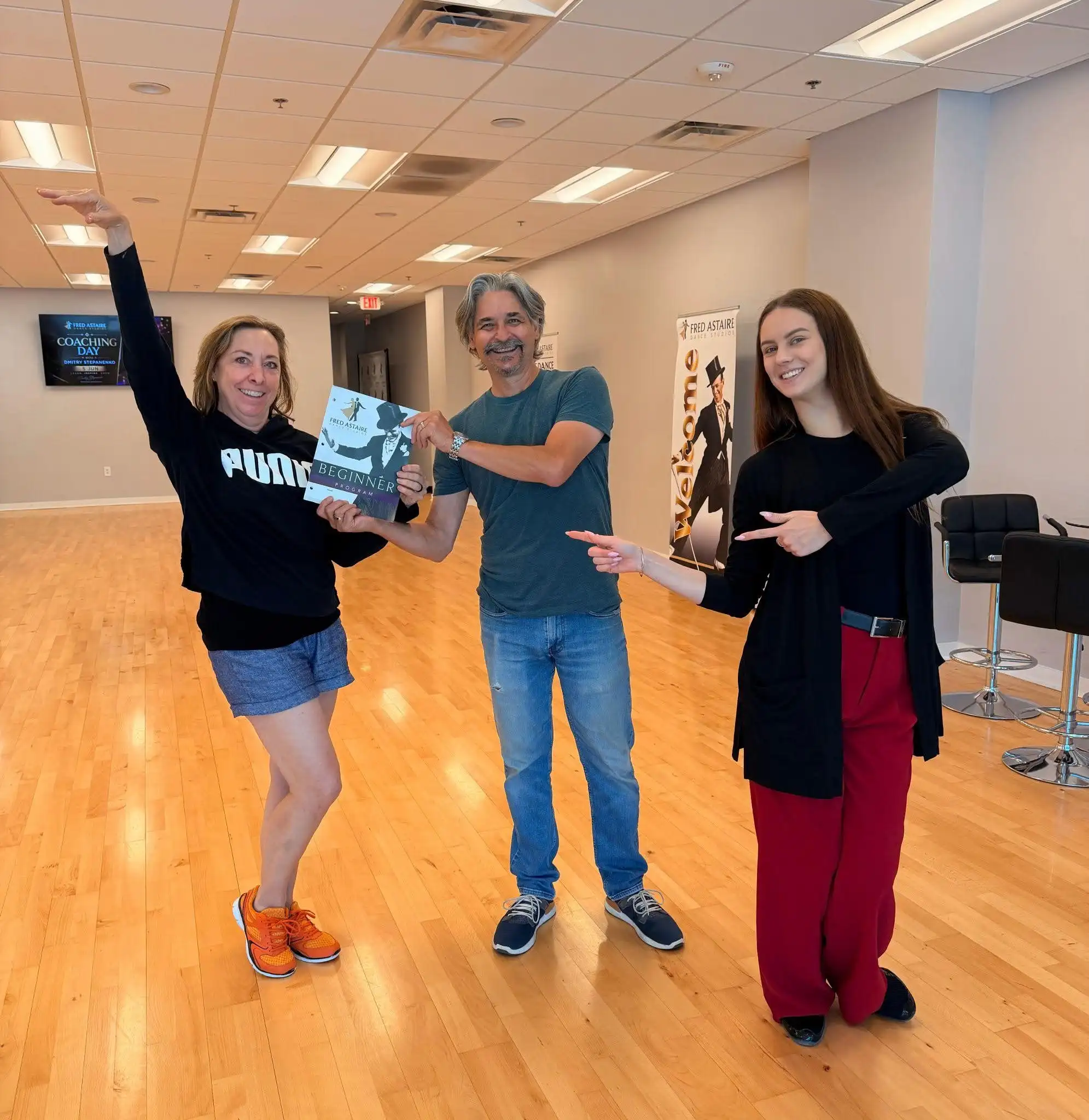 Adult students holding a beginner program guide during ballroom dance classes in Morrisville, NC.