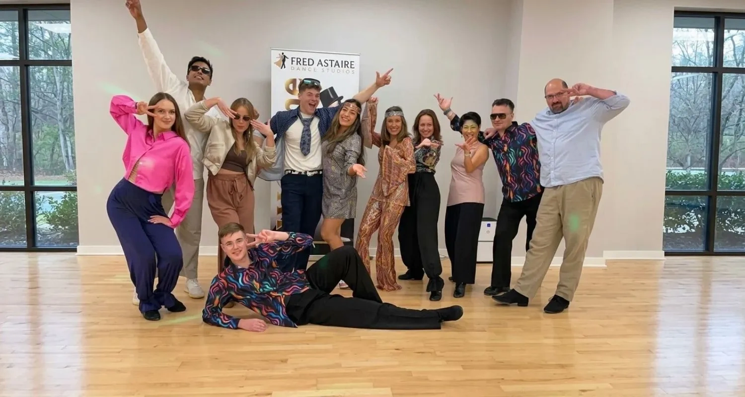 Students in retro outfits posing at a themed party at Fred Astaire Dance Studios Morrisville, NC.