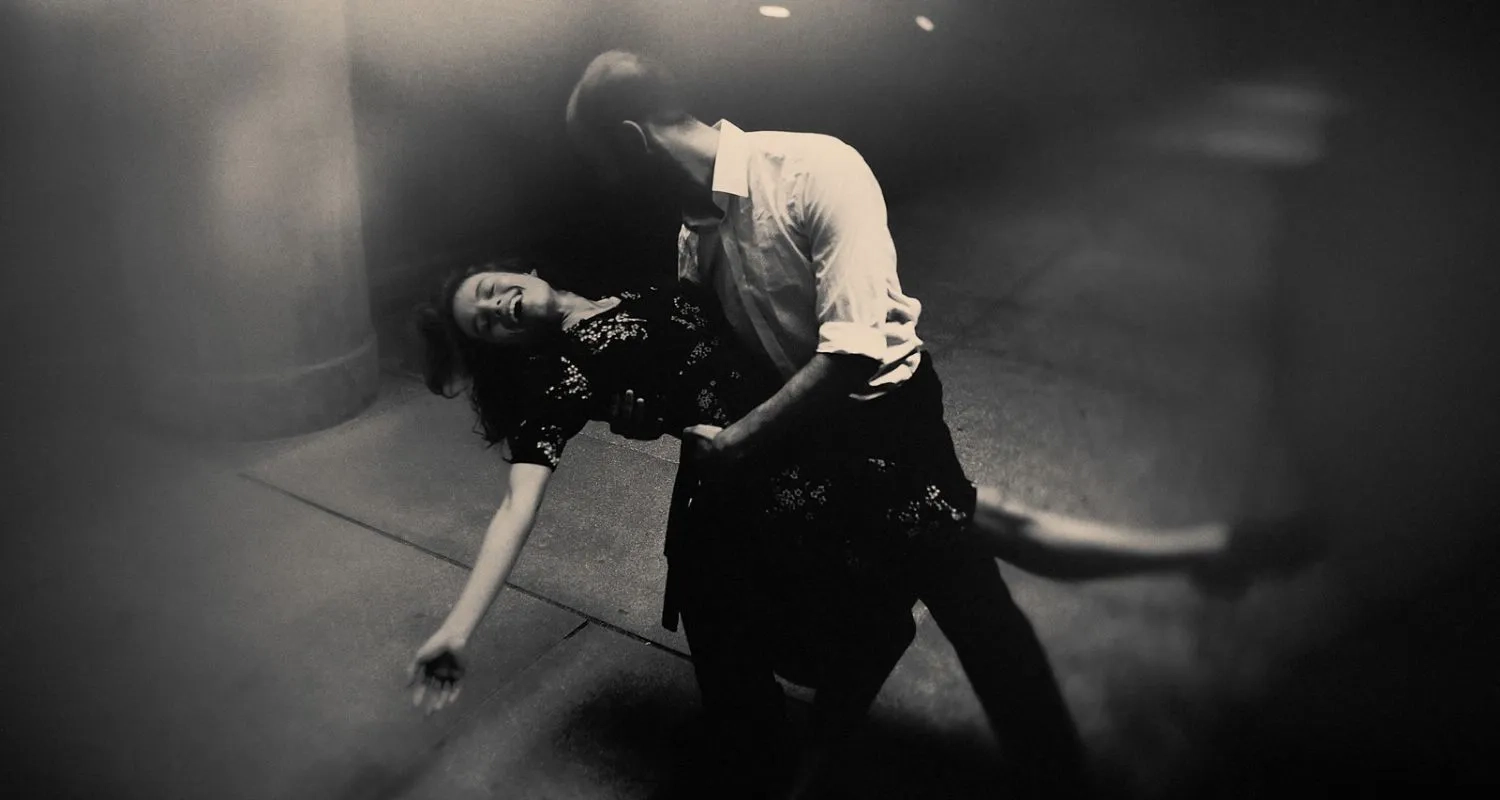 Dancer dipped backwards in her partner's arms during a Tango dip on a city street at night