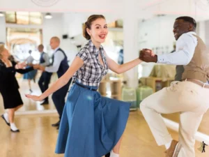 Young woman in blue skirt and plaid button up shirt takes east coast swing dance lessons in Raleigh NC.
