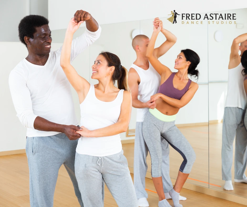 Couples practicing American Smooth and Rhythm dance styles during a partner dance class