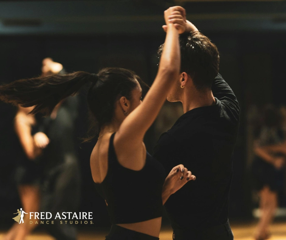 Ballroom dancing couple maintaining a connected dance frame while turning together on the dance floor.