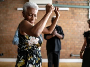 A woman enjoys dancing in a studio. Image accompanies the blog addressing the question "can I learn to dance as an adult"