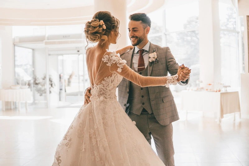 Bride and groom dance in sunlit room. Image complements the blog, Wedding Dance Lessons Timeline: When to Start Wedding Dance Lessons.