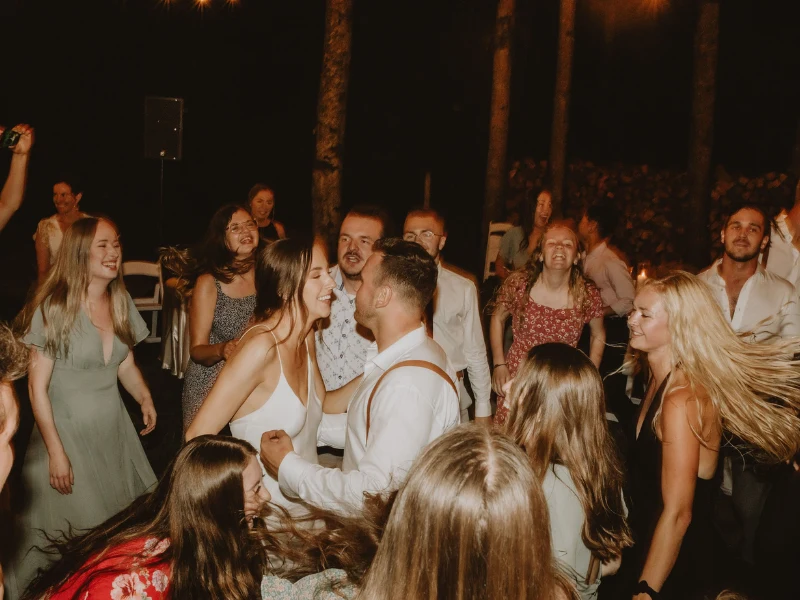 A vibrant night dance scene at an outdoor wedding reception with lively guests, celebrating how to choose first dance song for the couple.