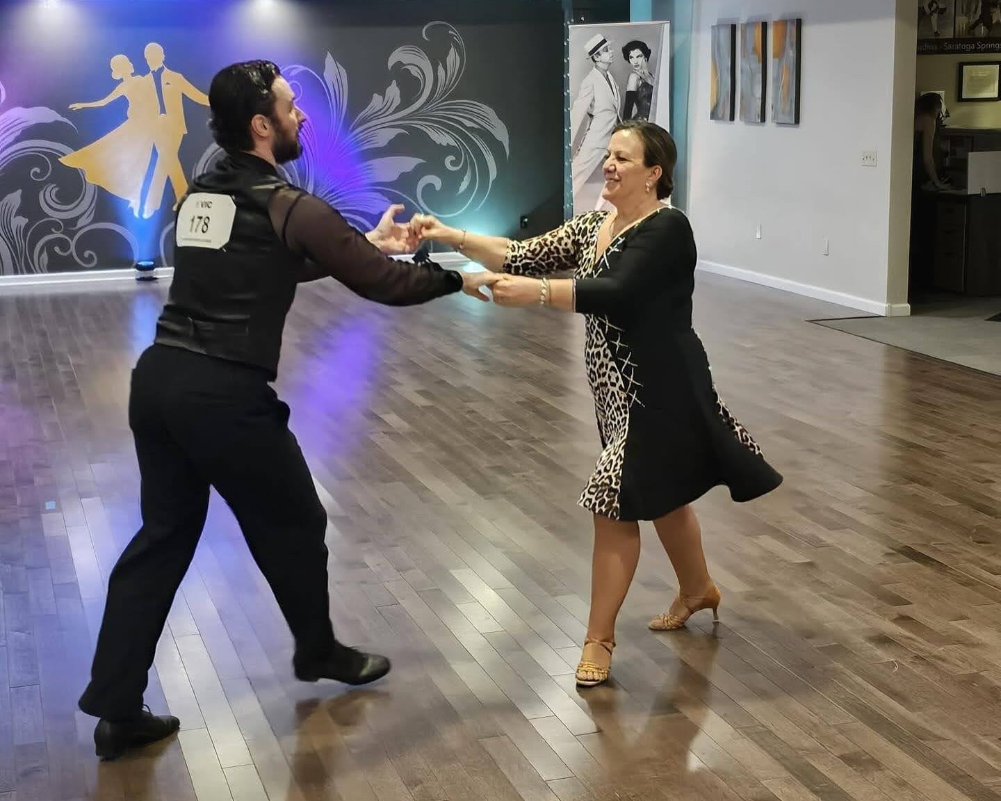 Adult student practicing salsa dancing with an instructor at a ballroom dance studio, learning partner steps, rhythm, and social dance technique in a welcoming environment.