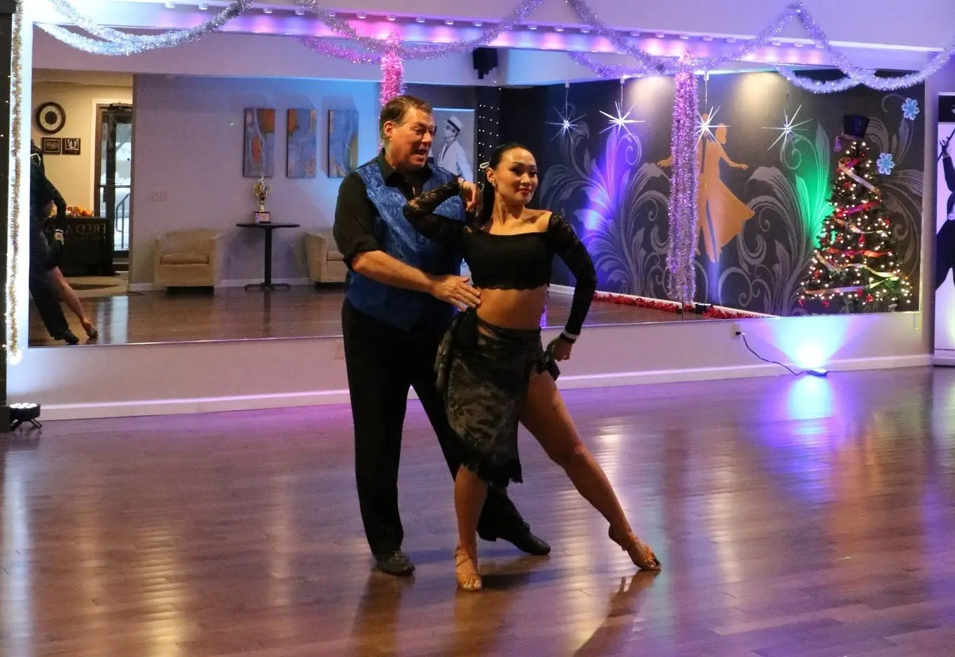 Couple performing during social dances in Saratoga Springs at a ballroom dance studio, showcasing partner dance technique and elegant Latin-inspired movements in a festive social setting.