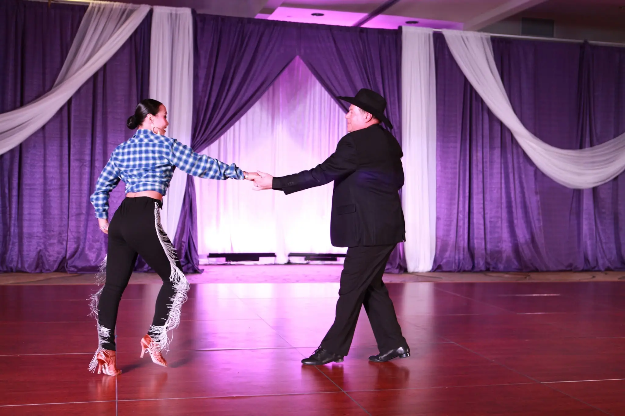Couple performing during social dances in Saratoga Springs at a ballroom dance studio, showcasing partner dance technique and elegant Latin-inspired movements in a festive social setting.