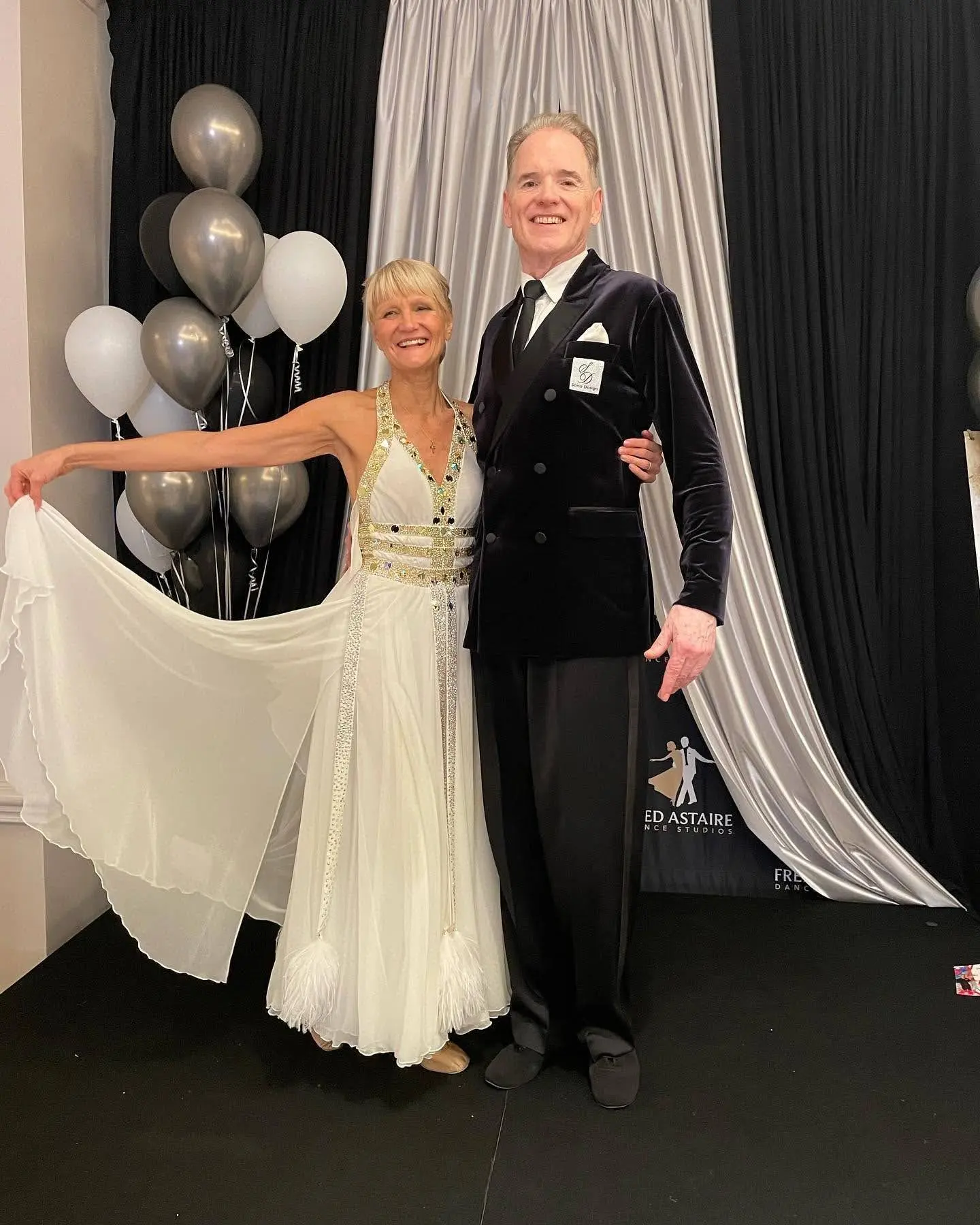 Private dance instructors from New York City posing together, the woman is wearing a beautiful white dress and the man is wearing a gorgeous tuxedo.